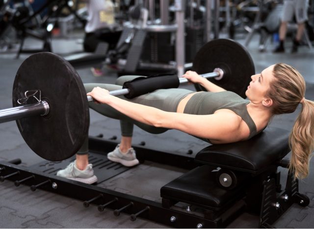 woman doing barbell hip thrusts at gym
