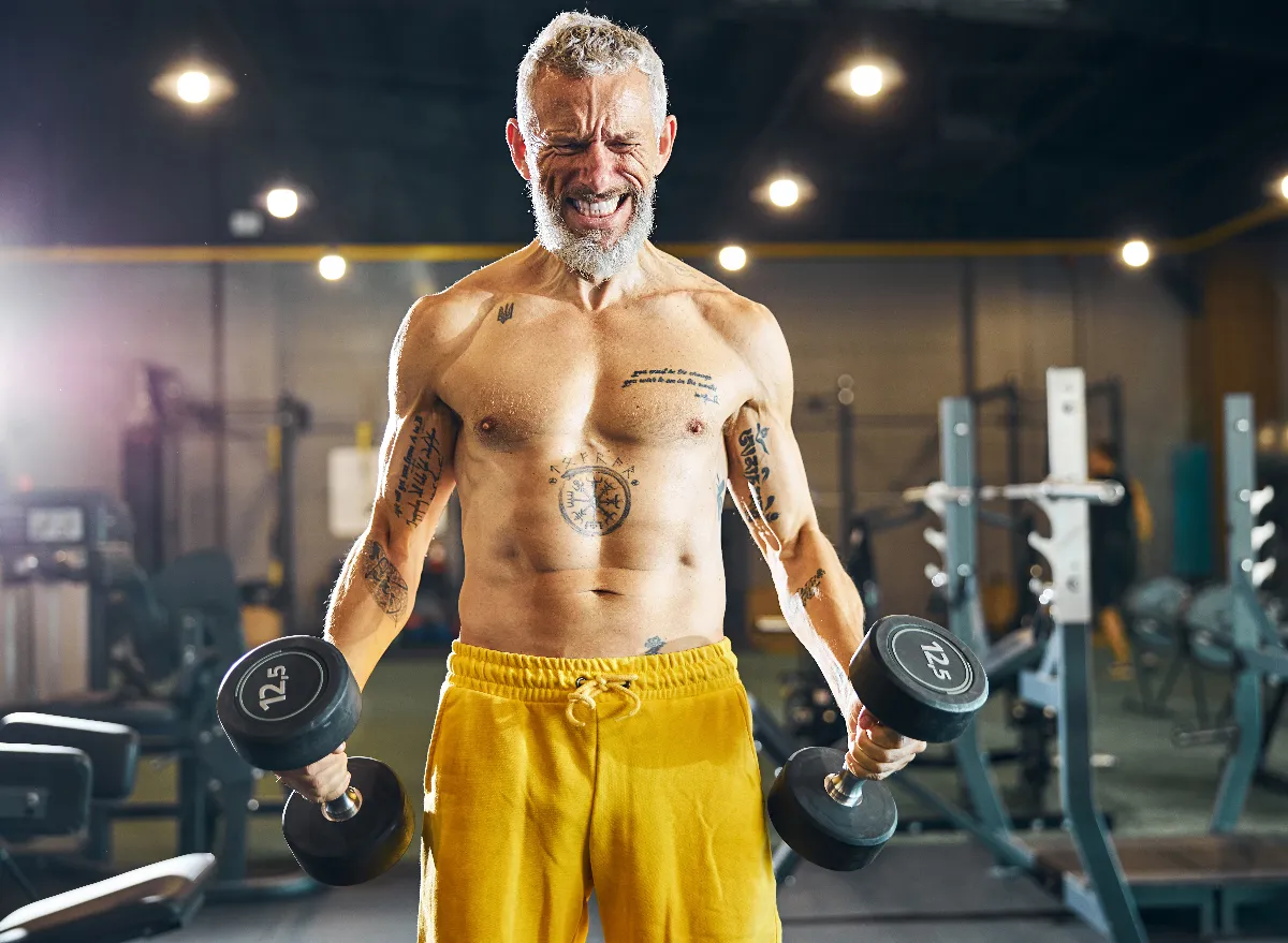 man overtraining, doing intense workout with dumbbells demonstrating bad fitness habits causing you to lose muscle mass
