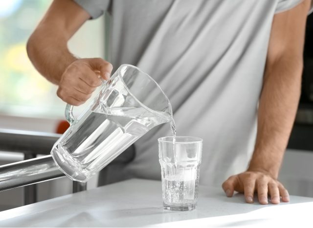 muž nalévající vodu v kuchyni