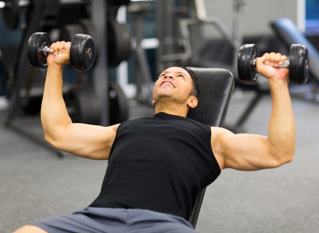 man lifting weights, dumbbell bench press, to get rid of pot belly fat