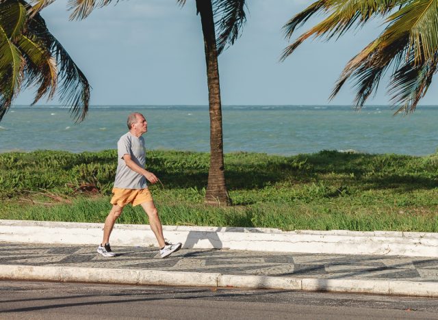 man walking getting exercise outdoors near tropical beach