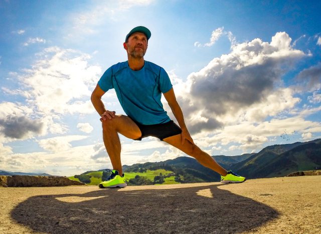 mature man doing side lunges outdoors