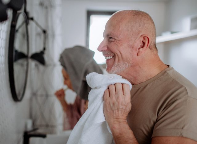 mature man drying face after washing it, concept of healthy lifestyle habits that are prematurely aging you
