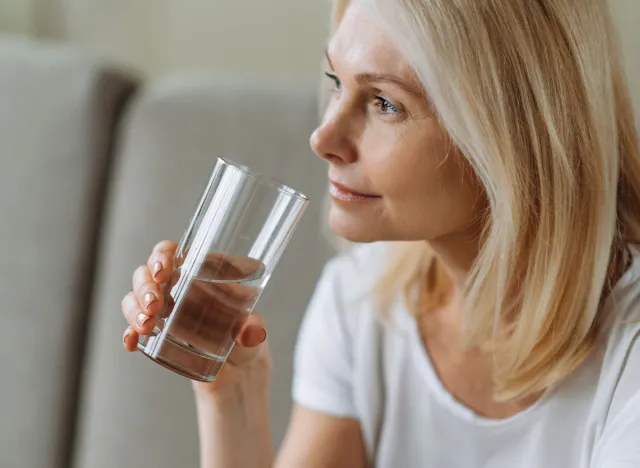 mogen kvinna dricka ett glas vatten hemma