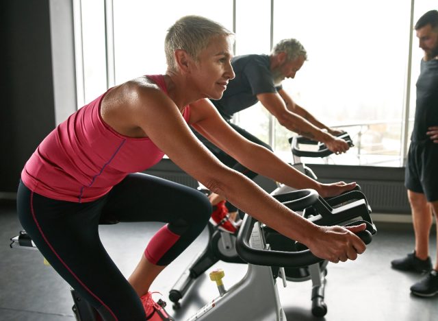 mature woman on exercise bike, concept of cardio workouts to increase stamina as you age