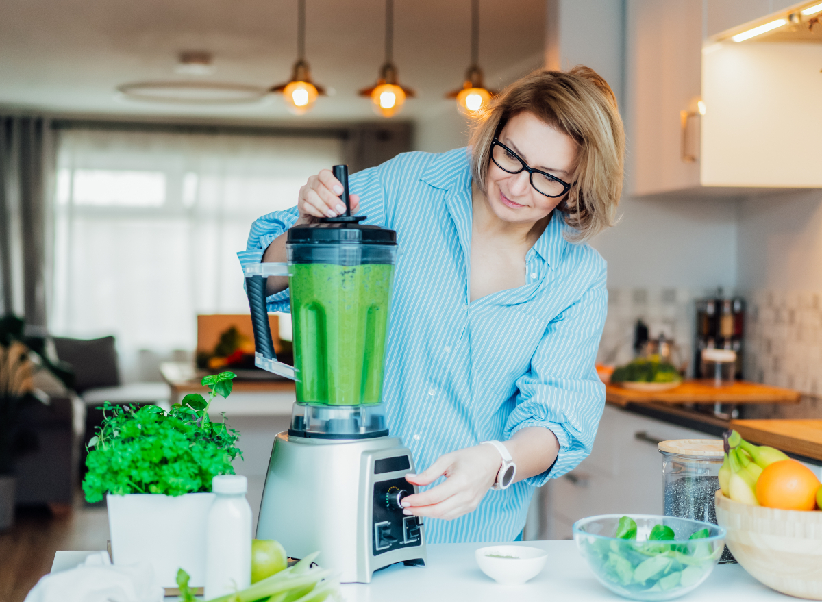 mature woman making healthy green breakfast smoothie, concept of morning routine to lose weight fast