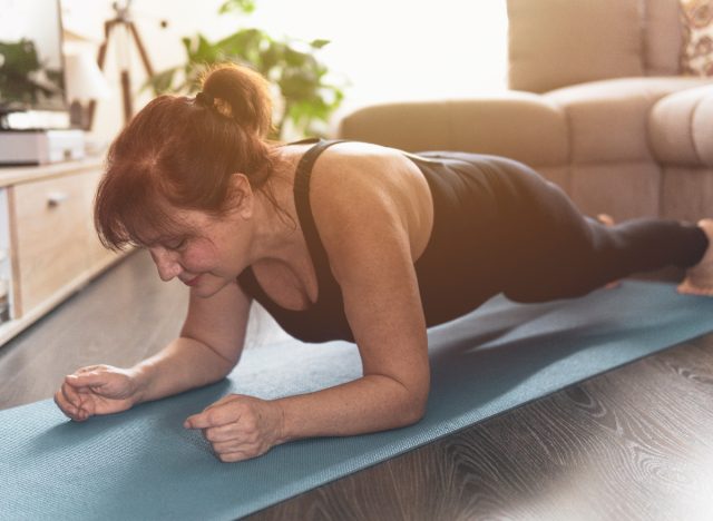 mature woman demonstrating plank exercise at home to increase your stamina after 50