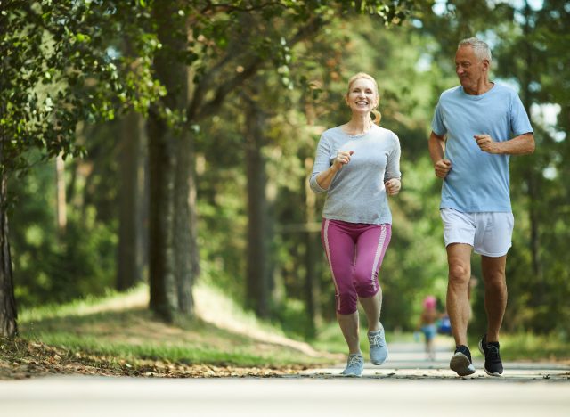 middle-aged couple jogging outdoors, concept of what's healthier in your 50s walking or jogging