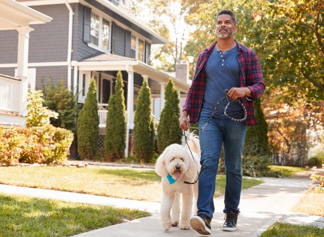 middle-aged man walking dog around neighborhood
