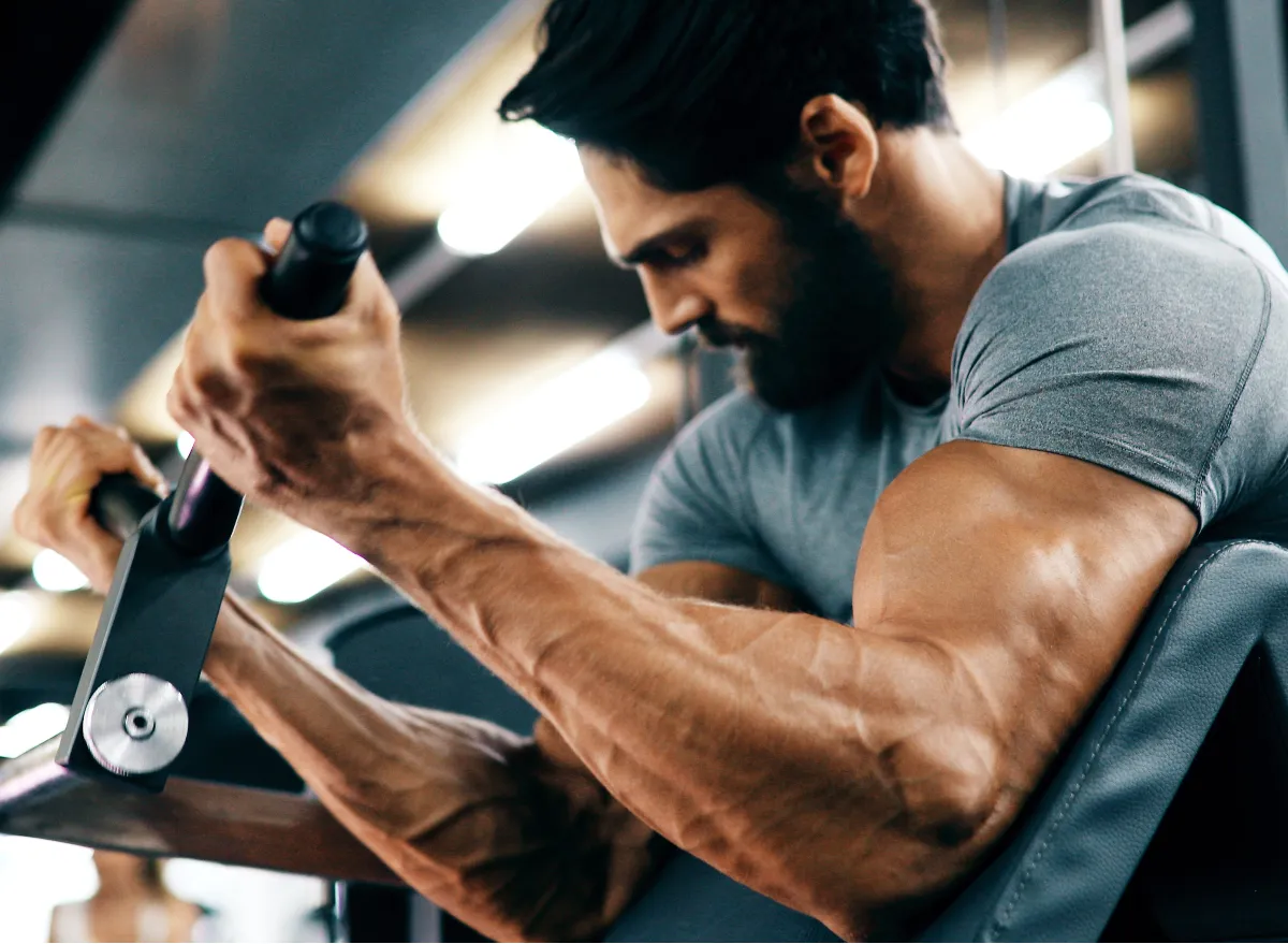 fit man demonstrating how to build muscle at gym machine