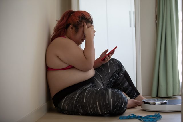 Plus-size woman sad by scale cyberbullying