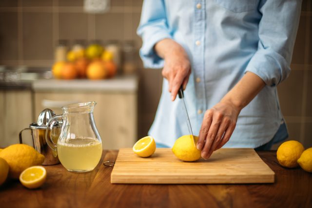 Young woman cutting lemons in the kitchen