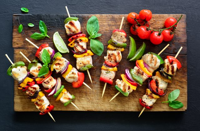 Chicken or turkey and vegetables cooked spicy skewers put on a board