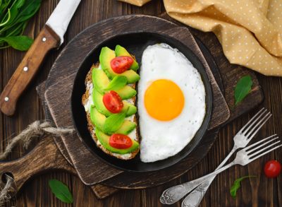 toast with avocado and tomatoes next to fried egg