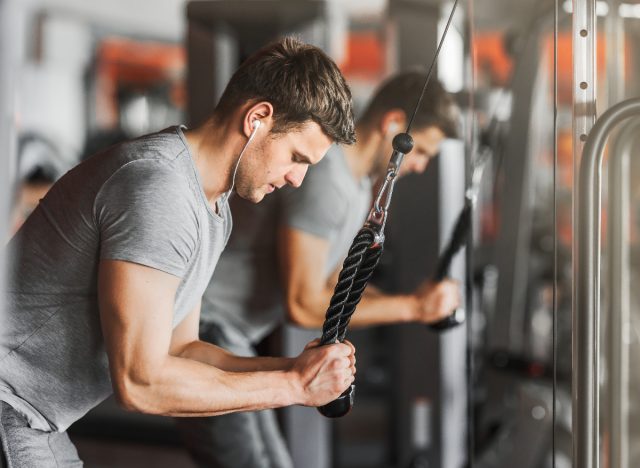 fitness man doing tricep rope extension at the gym to get bigger arms