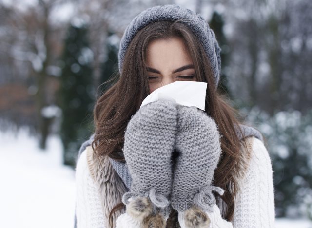 woman blowing nose out in snow, cold season
