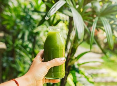 woman's hand holding green juice