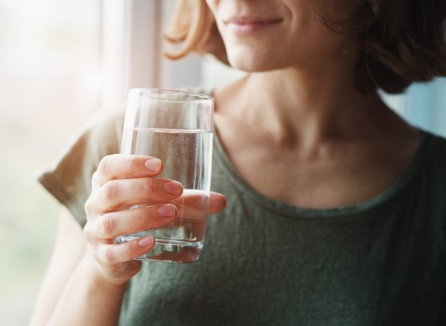 close-up woman holding water glass, concept of belly fat loss tips for women