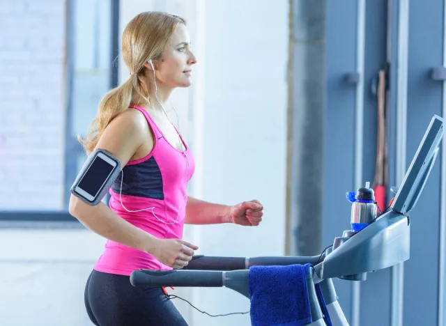 Fit blonde woman doing incline treadmill walking exercises
