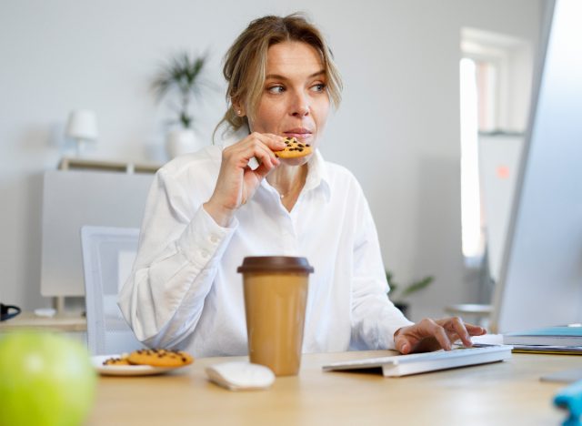 mulher comendo biscoito de chocolate, comendo lanches estúpidos enquanto trabalha