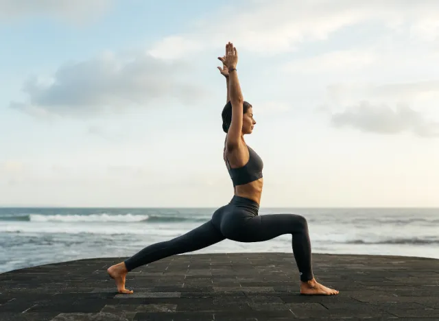 woman does mobility stretches, lunges by the ocean