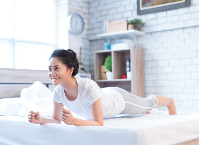 woman doing planks in bed, demonstrating fat-burning exercises to do in bed