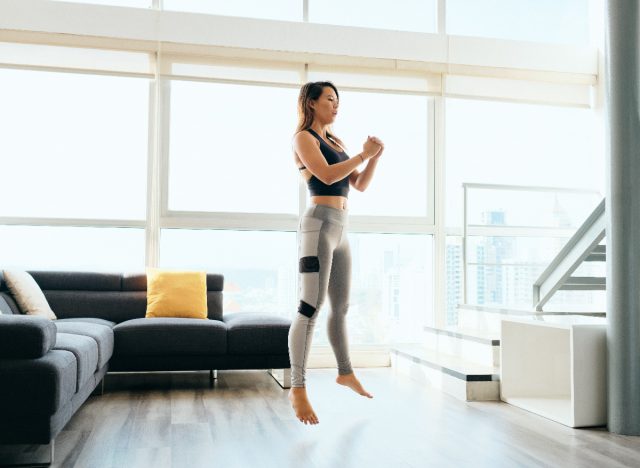 Woman doing squat jumps at home to fight overweight in winter