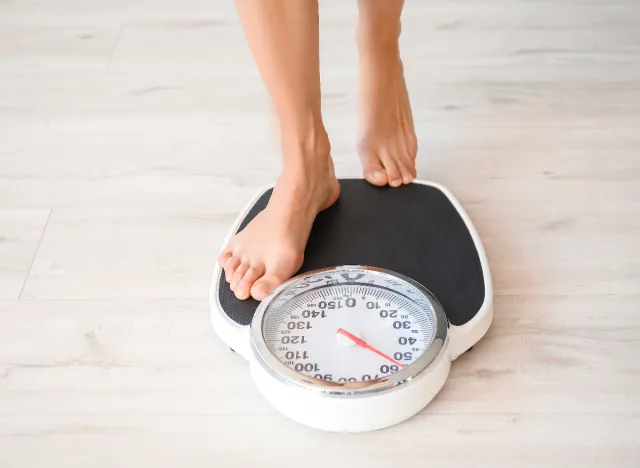 woman stepping on scale, keeping track of her weight to lose weight before breakfast