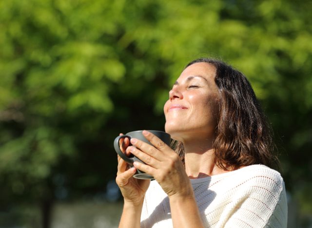happy woman drinking tea in morning sunlight outdoors