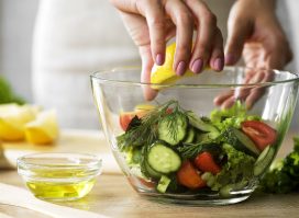 close-up woman squeezing lemon juice onto veggies, concept of how to lose 10 pounds through diet