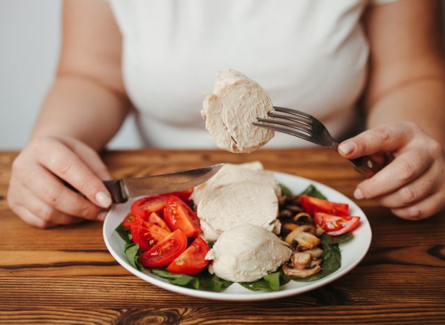 woman cutting and eating chicken with vegetables, lean chicken is one of the best foods to increase physical fitness