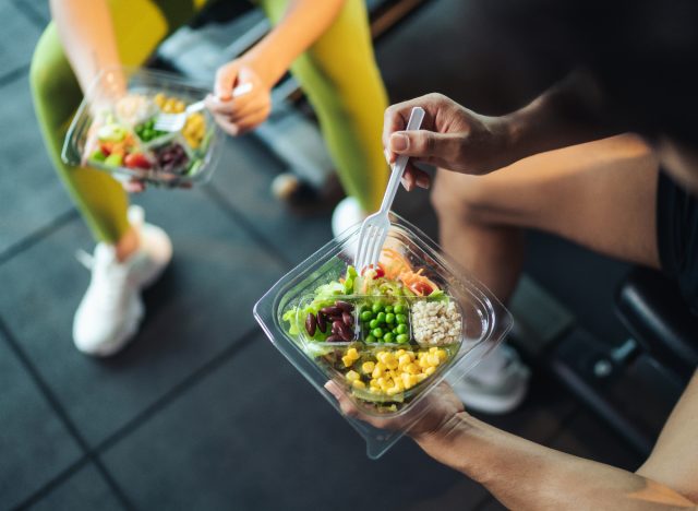 fitness couple eating salads at the gym