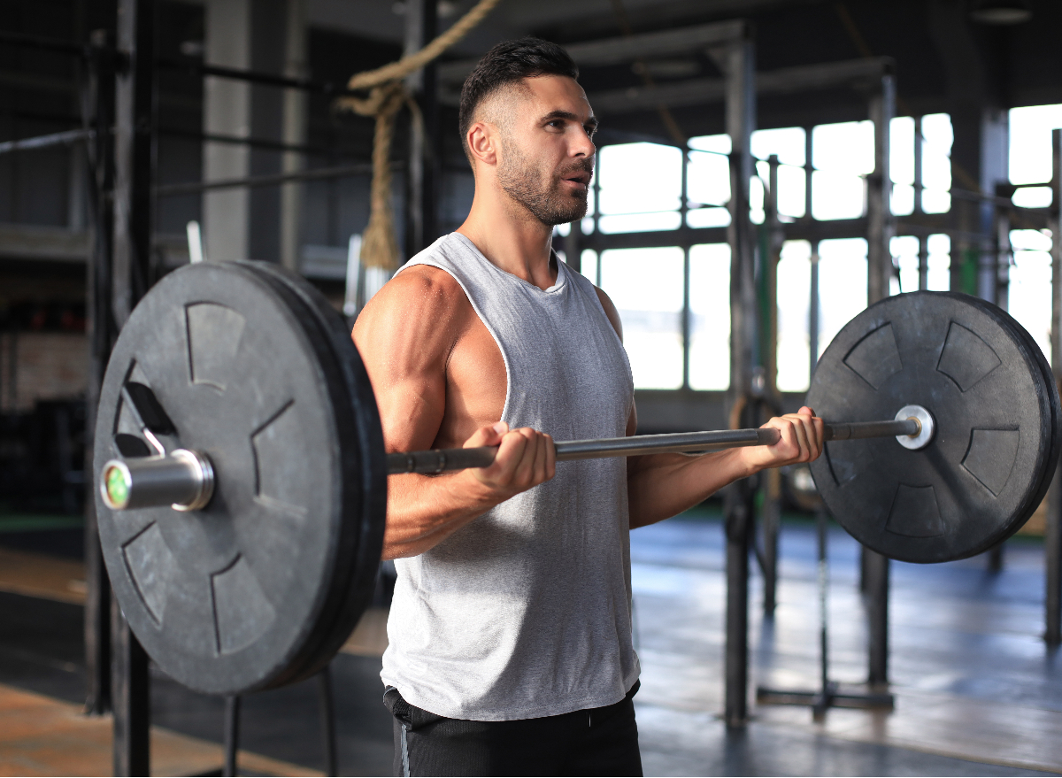 man holding barbell in gym, concept of doing a drop set