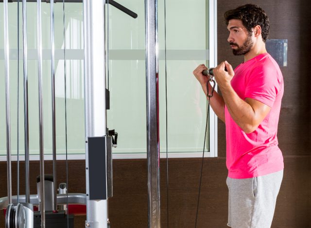 fitness man doing cable bicep curl exercises to build strength and muscle at gym