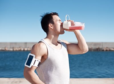 fitness man drinking protein shake outdoors, concept of eating mistakes for building muscle, over-doing it on protein