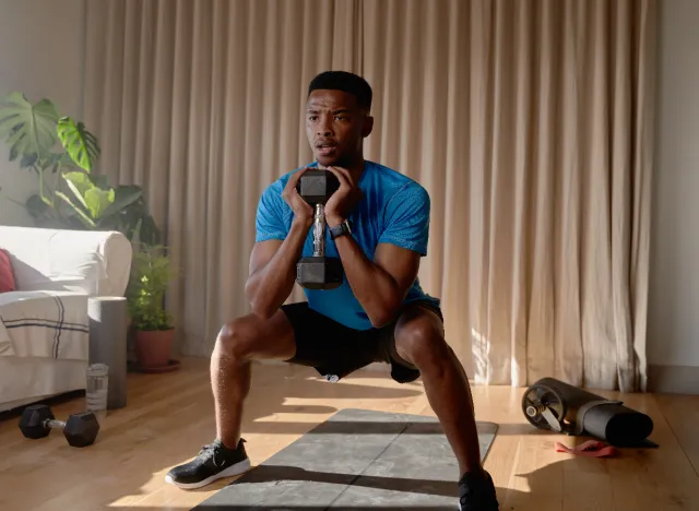 man demonstrating dumbbell squat to get rid of hanging belly fat