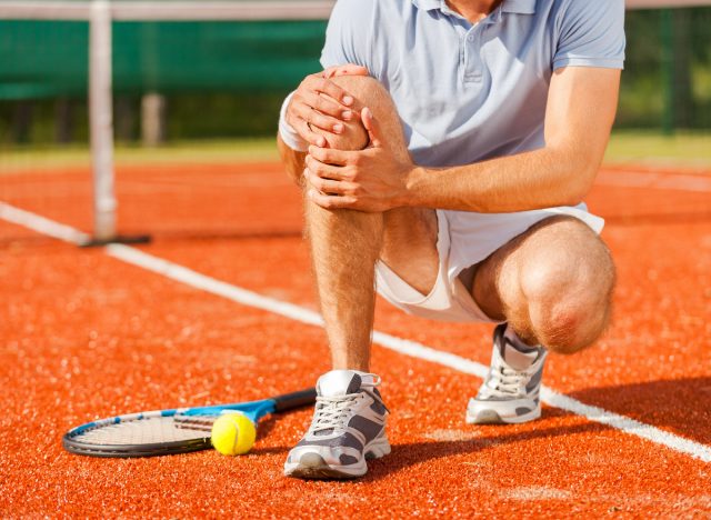 close-up man holding knee, injury on tennis court