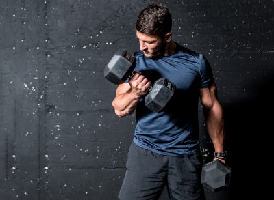 muscular fitness man lifting dumbbells, concept of mistakes when working out with dumbbells