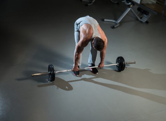 man picking up barbell of the floor
