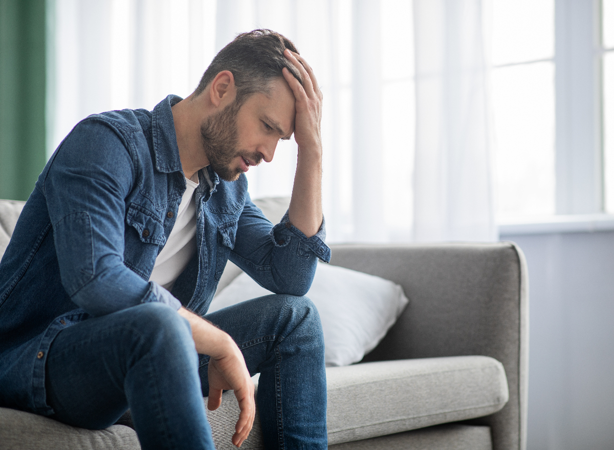 middle-aged man sitting on couch, concept of negative side effects of a sedentary lifestyle