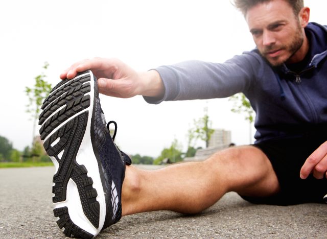 man doing stretches outdoors, cooling down after workout