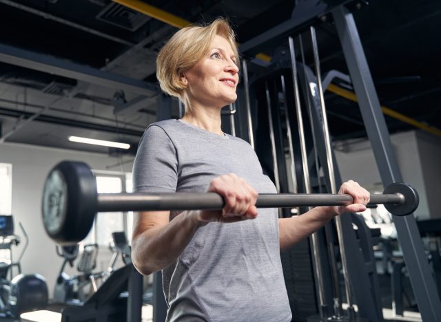 mature woman holding barbell demonstrating exercises that change your body shape after 50