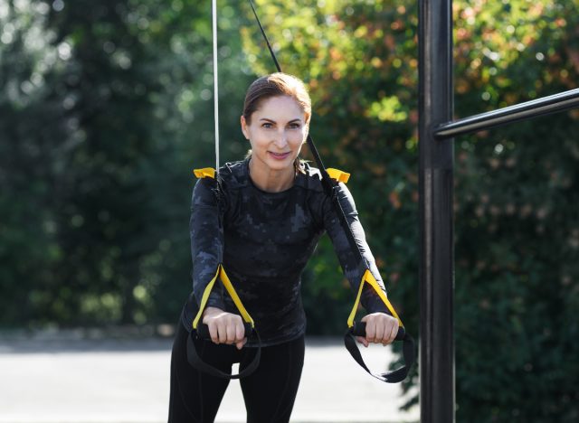 mature woman doing TRX pushups outdoors