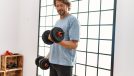 middle-aged man lifting dumbbells in bright room, concept of how to get stronger after 40