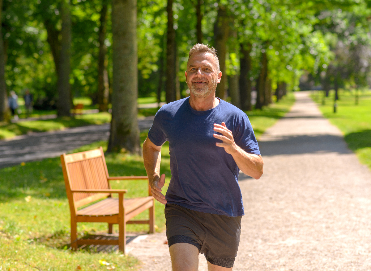 middle-aged man running through sunny park, concept of what running daily does to your body