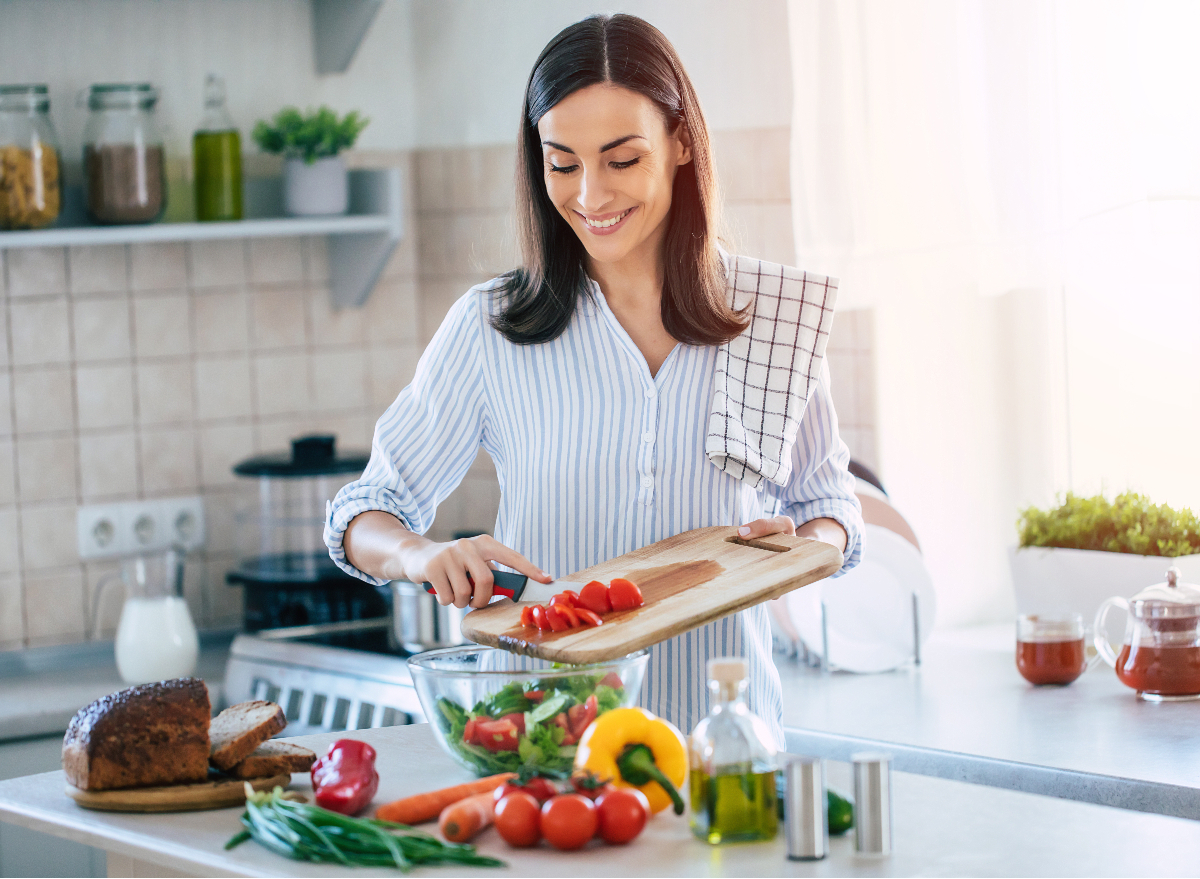 happy woman cutting up veggies for salad, diet habits for weight loss