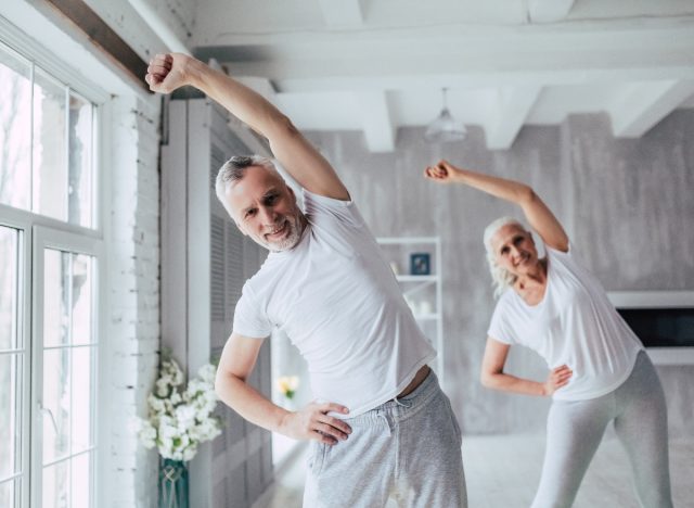 mature senior couple doing yoga mobility exercises