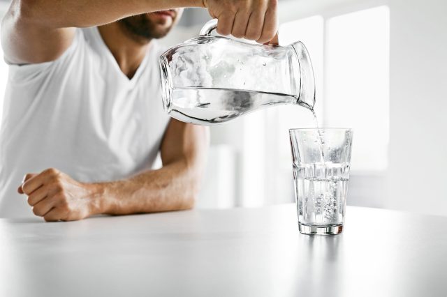 athletic man pouring a glass of water