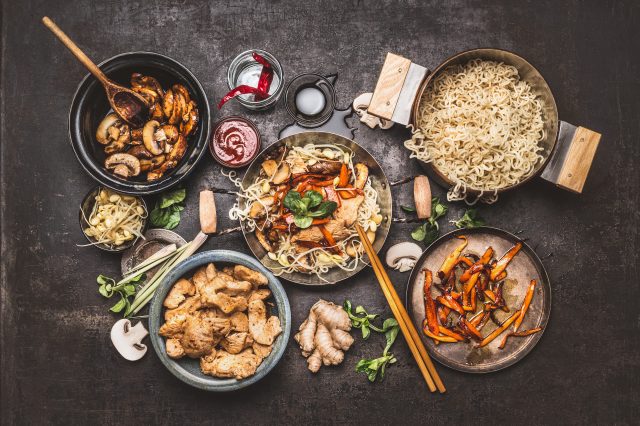 Asian cooking; wok with noodles, chicken, and vegetables with spices and sauces 