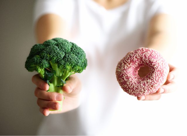 close-up woman holding up broccoli and donut, healthy balance concept of best weight loss tips